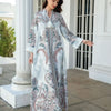 Une femme modélise une élégante abaya perlée en diamant blanche et bleue à motifs floraux, à l'extérieur.