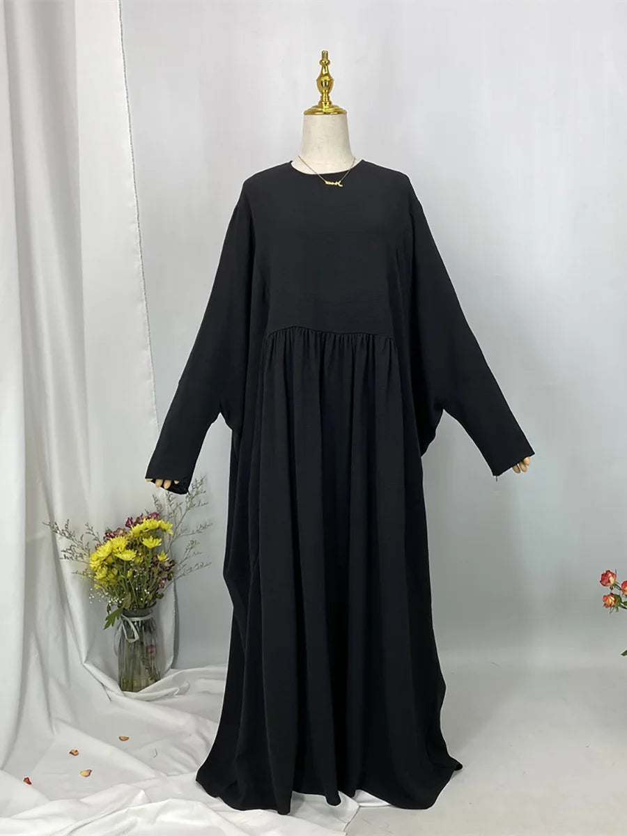 Schwarze, elegante Batwing-Abaya auf einem Mannequin vor weißem Hintergrund.