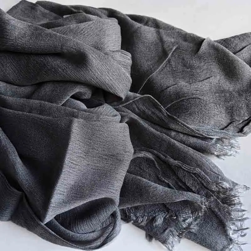 Foulard hijab en viscose coton gris foncé avec pompons drapé dans le tissu.