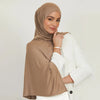A woman wearing a beige stretchy jersey plain hijab scarf and a white blazer.