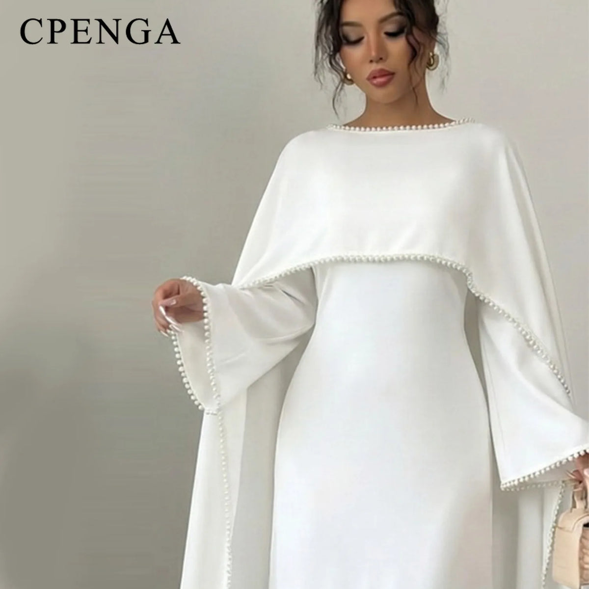 Eine Frau in einem eleganten weißen, bescheidenen Abaya-Kleid mit langen Ärmeln und zarten Perlenverzierungen.