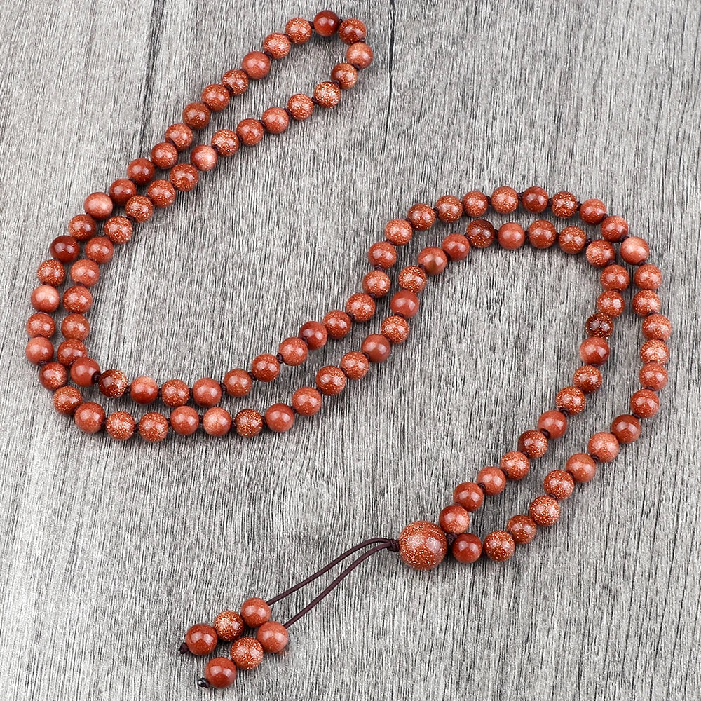 Eine Kette aus rötlich-braunen, natürlichen Steinchen, auf einer grauen Holzoberfläche.