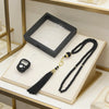 A black Islamic tasbih prayer beads with gold accents and a digital counter bracelet displayed on a light wooden tray.