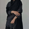 Eine Frau trägt ein elegantes schwarzes Polka-Dot Abaya-Cardigankleid mit goldenen Schmuck.