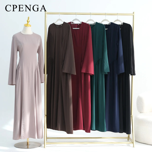 Elegant long-sleeve abayas in various colors displayed on a gold hanger rack