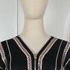 Vestido abaya negro con ribete y bordado plateado, mostrado en un maniquí.