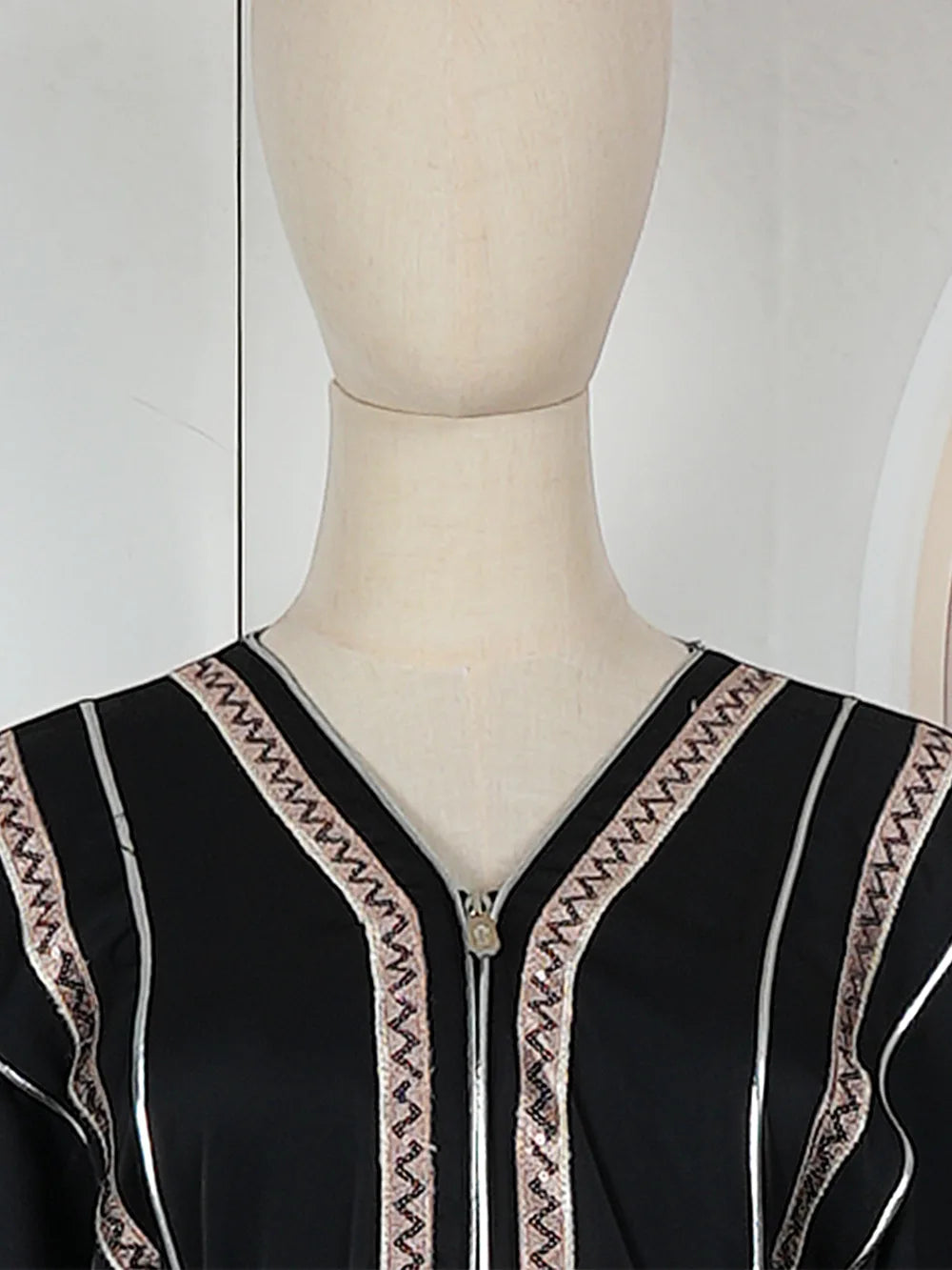 Vestido abaya negro con ribete y bordado plateado, mostrado en un maniquí.