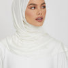 Eine Frau mit weißem Jersey-Hijab-Schal, die zur Seite blickt.