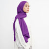 Eine Frau trägt einen lila, weichen Baumwoll-Jersey Instant-Hijab-Schal über einem weißen Oberteil.