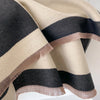 Pañuelo pashmina a rayas beige y negro, drapeado suavemente.