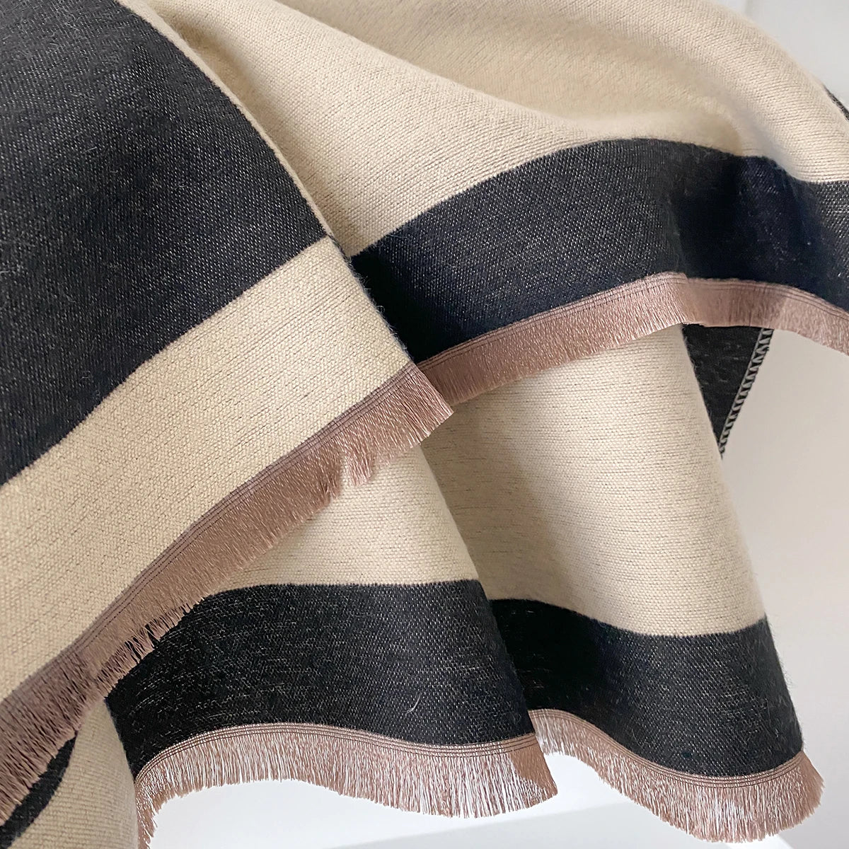 Pañuelo pashmina a rayas beige y negro, drapeado suavemente.