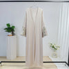 Beige bestickte, lockere Kaftan-Abaya auf einem Hänger vor weißem Hintergrund.