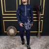 Un homme portant un costume de mariage musulman traditionnel africain bleu marine avec des accents dorés, devant un cadre dor