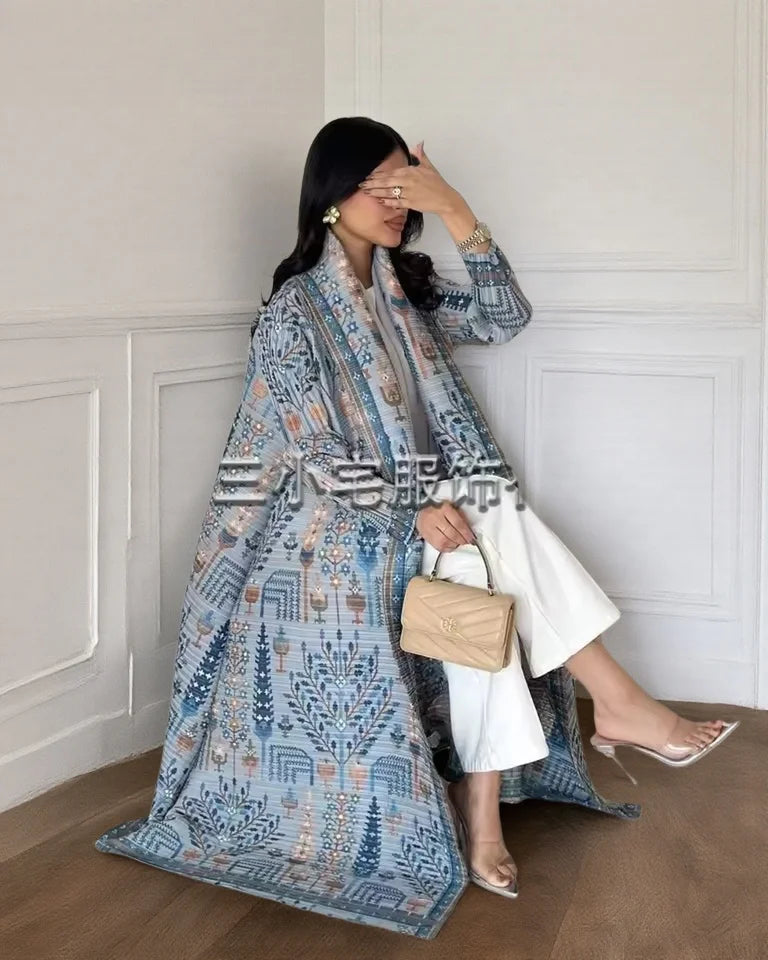 Una mujer vistiendo un cárdigan abaya plisado de color azul y blanco en una luz clara.