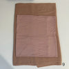 A folded soft mauve hijab set made of a smooth fabric is displayed on a white surface.
