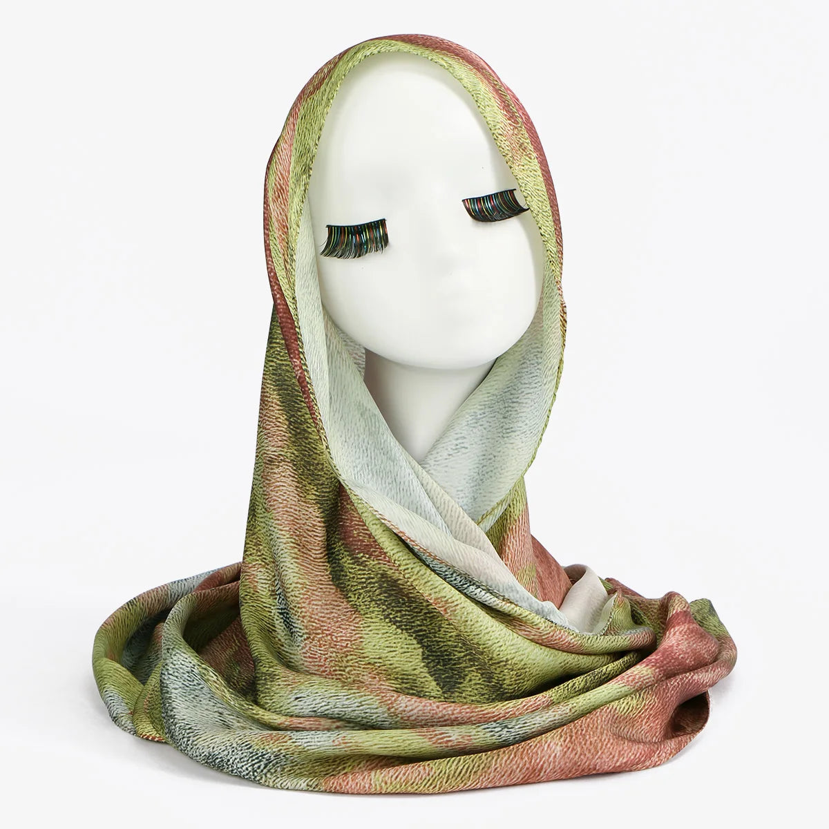 Un modèle portant un foulard hijab en soie satinée imprimé dans des tons de vert, rose et beige.