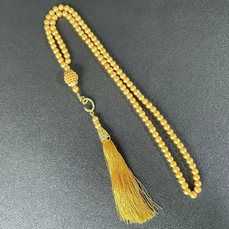 Langer goldener Perlenfaden mit Quaste, verwendet als islamische Gebetsrosario-Armband.
