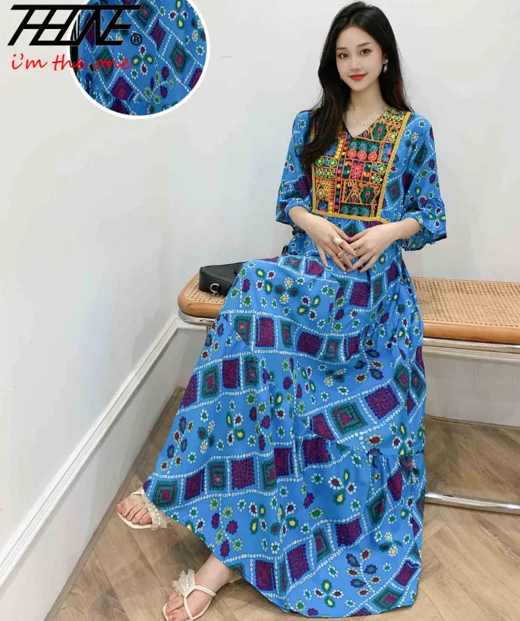 Eine Frau modelliert ein blau-lila Boho-besticktes Maxi-Kleid mit Blumenmustern.