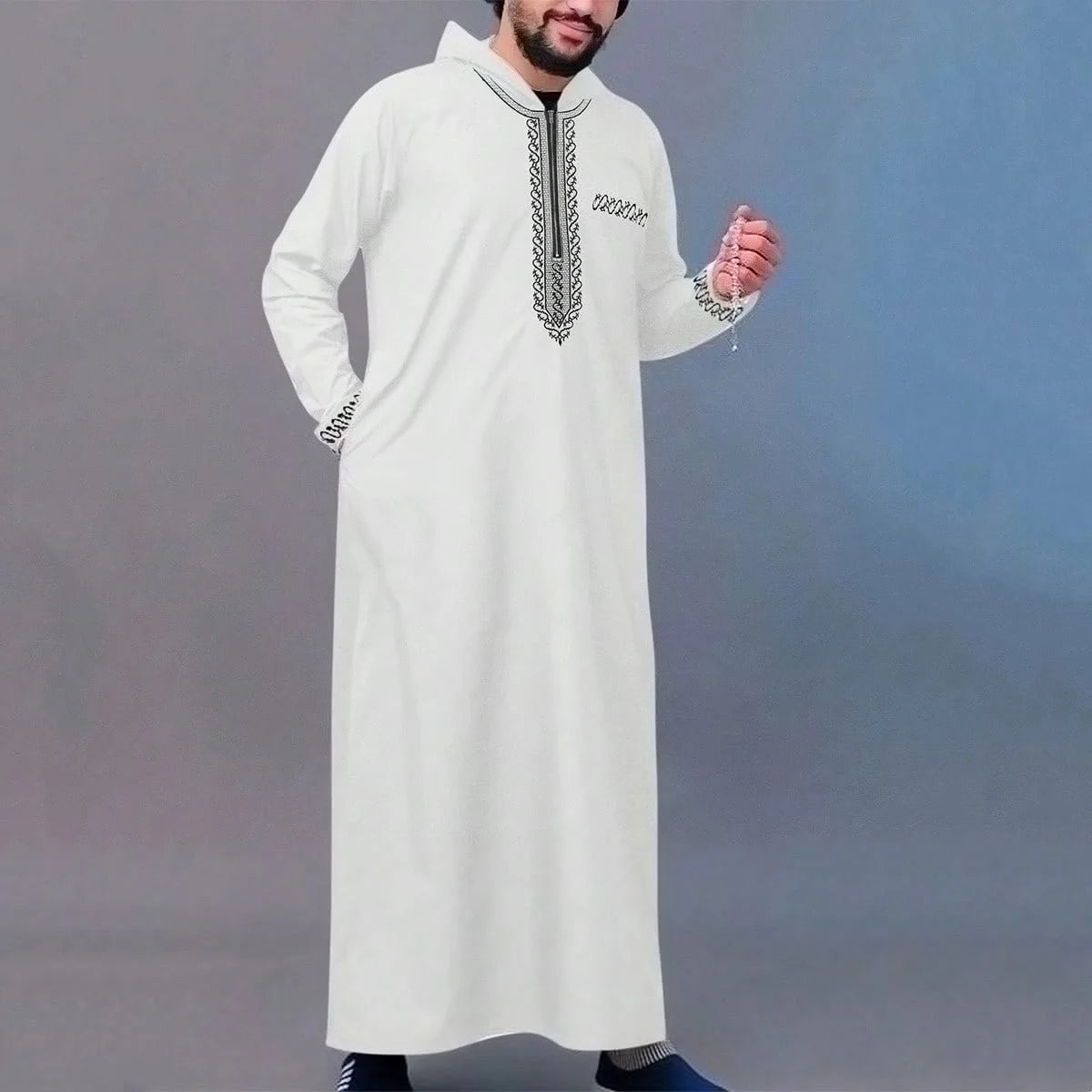 A man wearing a white Moroccan ethnic thobe with a stand collar and silver embroidery.