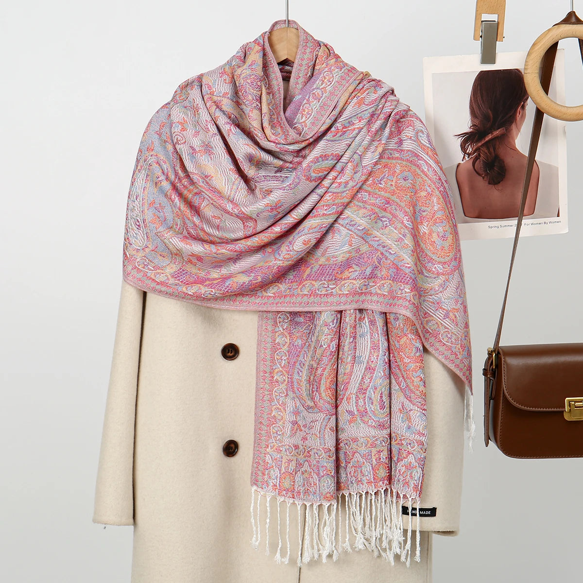 Chal de bordado paisley rosa y morado sobre un abrigo beige.