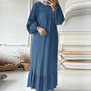 Une femme portant une longue robe maxi en denim bleu avec ourlet à volants et un hijab beige clair.