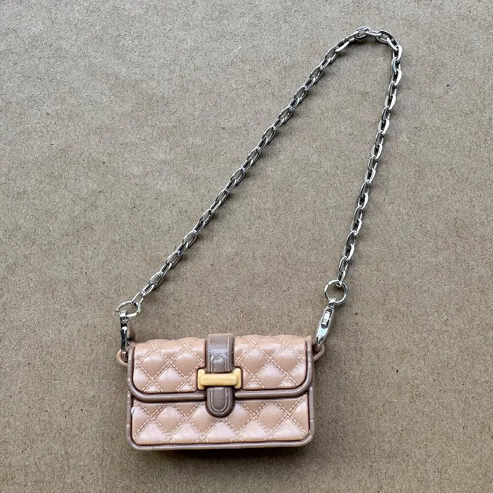 Bolso de cuero acolchado rosa claro con cierre dorado y correa de cadena plateada.