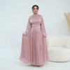 Une femme modélise une abaya de couleur rose poussiéreux fluide avec un col haut et une ceinture ornée à la taille.