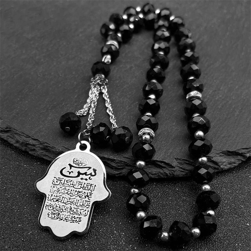 Clé porte-clés islamique arabe en perles noires, Allah, suspendue sur une surface sombre.