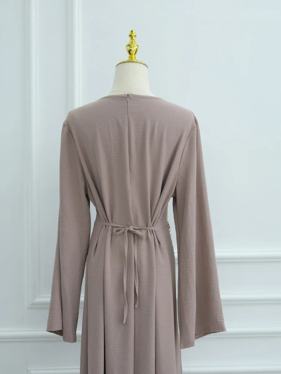 Une abaya beige à cordon de serrage affichée sur un mannequin.