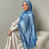Una mujer vistiendo un pañuelo de hijab a rayas acuareladas azules y blancas con un vestido beige claro.
