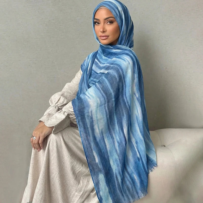 Una mujer vistiendo un pañuelo de hijab a rayas acuareladas azules y blancas con un vestido beige claro.