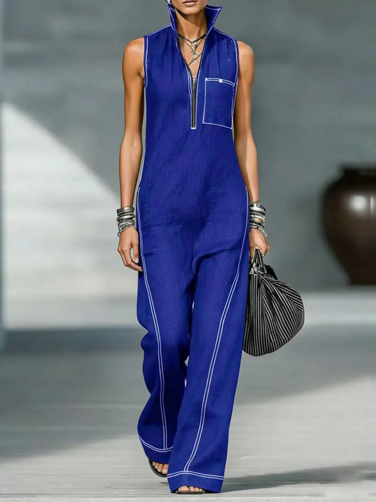Una modelo vistiendo un top de punto sin mangas y cuello azul real con bolsillos de parche y pantalones a juego.