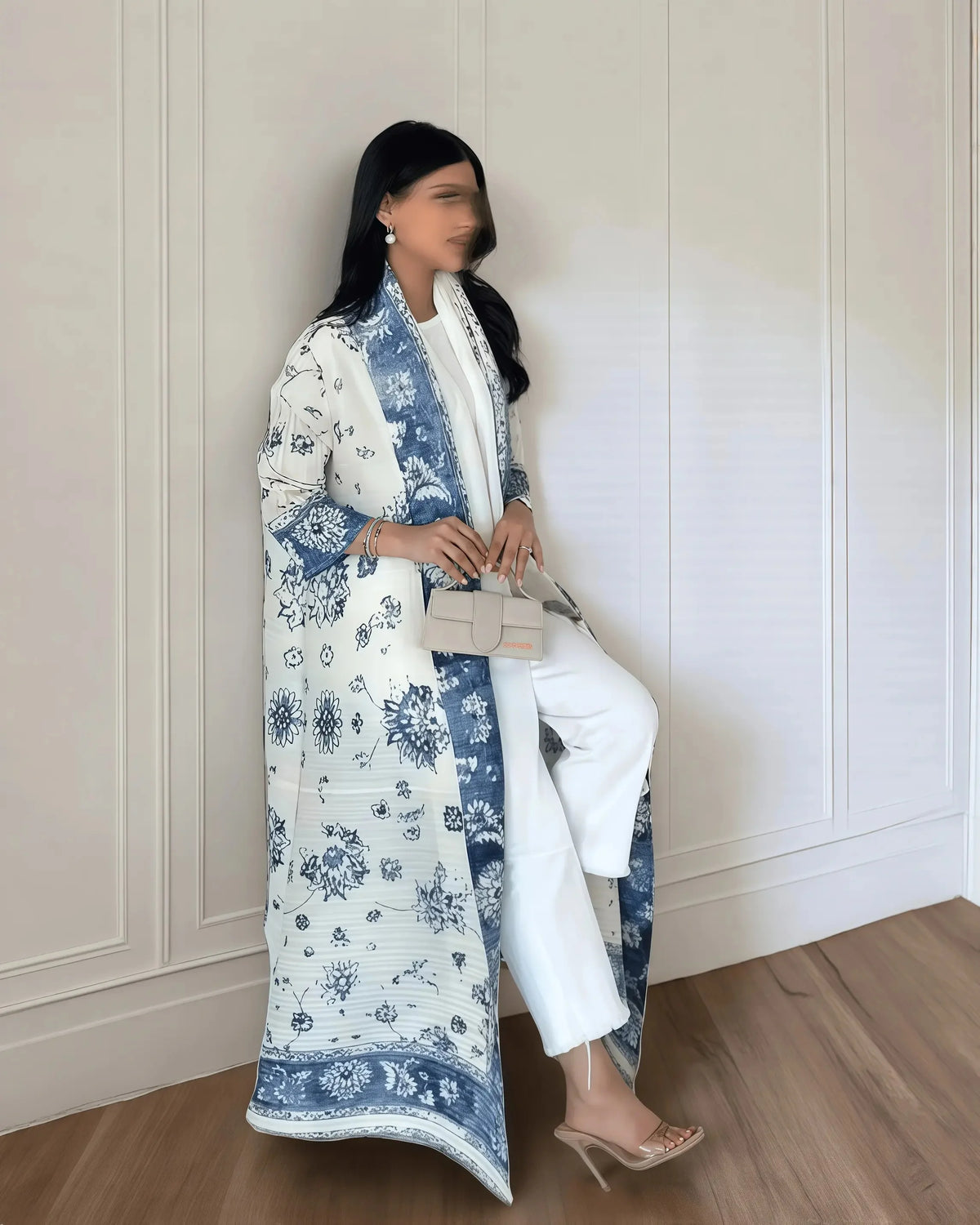 Una mujer vistiendo un cárdigan abaya plisado de color blanco y azul estampado, de pie en interiores.