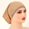 Modelo vistiendo unhiyab de algodón elástico modal beige con ribete dorado brillante en la frente.