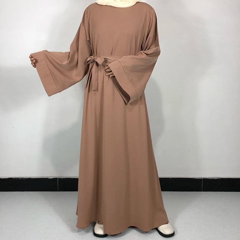 Une longue robe abaya taupe fluide avec une ceinture, présentée sur un fond clair.
