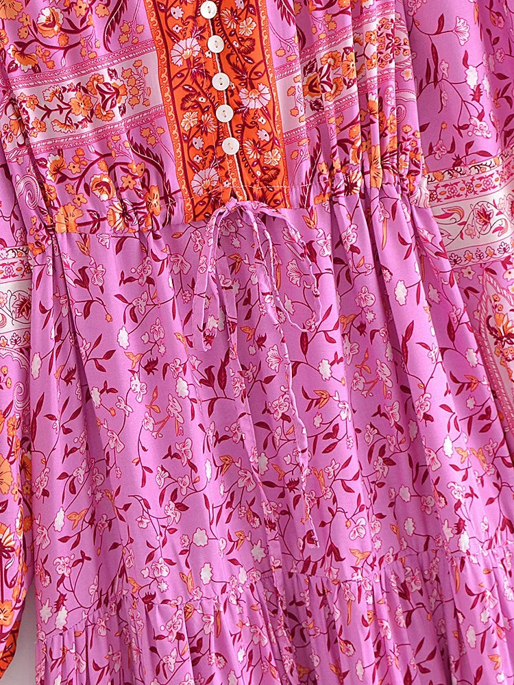A close-up of a pink floral maxi dress featuring intricate embroidery and lantern sleeves.