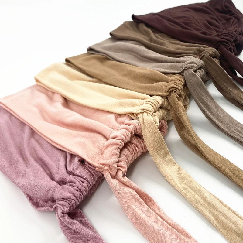 Eine Kollektion von mehrfarbigen Inner-Hijab-Turbanen in verschiedenen Schattierungen von Mauve, Beige und Braun.