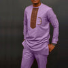 Un homme portant un costume de mariage musulman traditionnel africain violet avec broderies dorées et pantalon assorti.