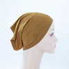 Ein Model trägt eine einfarbige olivgrüne Bambus-Jersey-Turbanmütze auf dem Kopf.