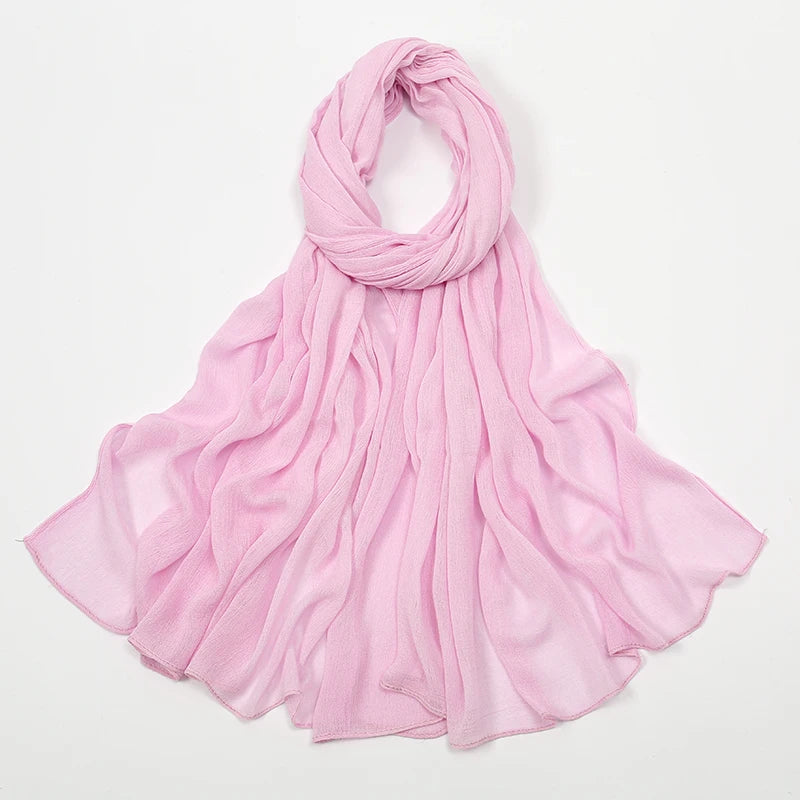 Écharpe en rayon rose doux et froissé drapée autour du cou et flottant sur les épaules.