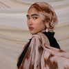 Une femme portant un foulard hijab en polyester doux avec des motifs abstraits marron et beige.