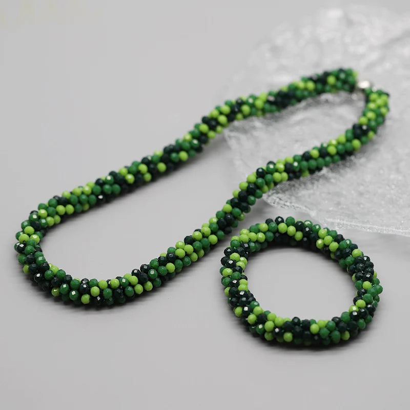 Grüne und schwarze Perlenarmband auf weißem strukturiertem Stoff.