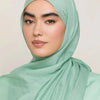 Une femme portant un foulard modal vert menthe, regardant directement l'appareil photo.