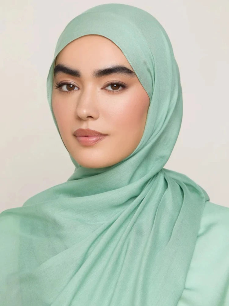 Une femme portant un foulard modal vert menthe, regardant directement l'appareil photo.