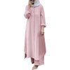 Una mujer vistiendo un largo vestido abaya rosa claro de botones con mangas fruncidas y una blusa gris claro.