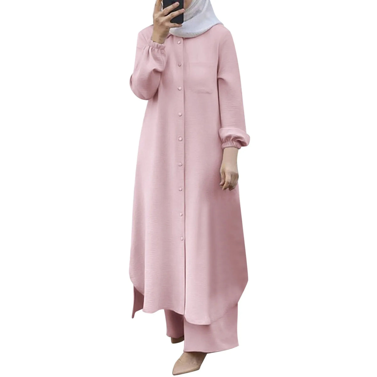 Una mujer vistiendo un largo vestido abaya rosa claro de botones con mangas fruncidas y una blusa gris claro.