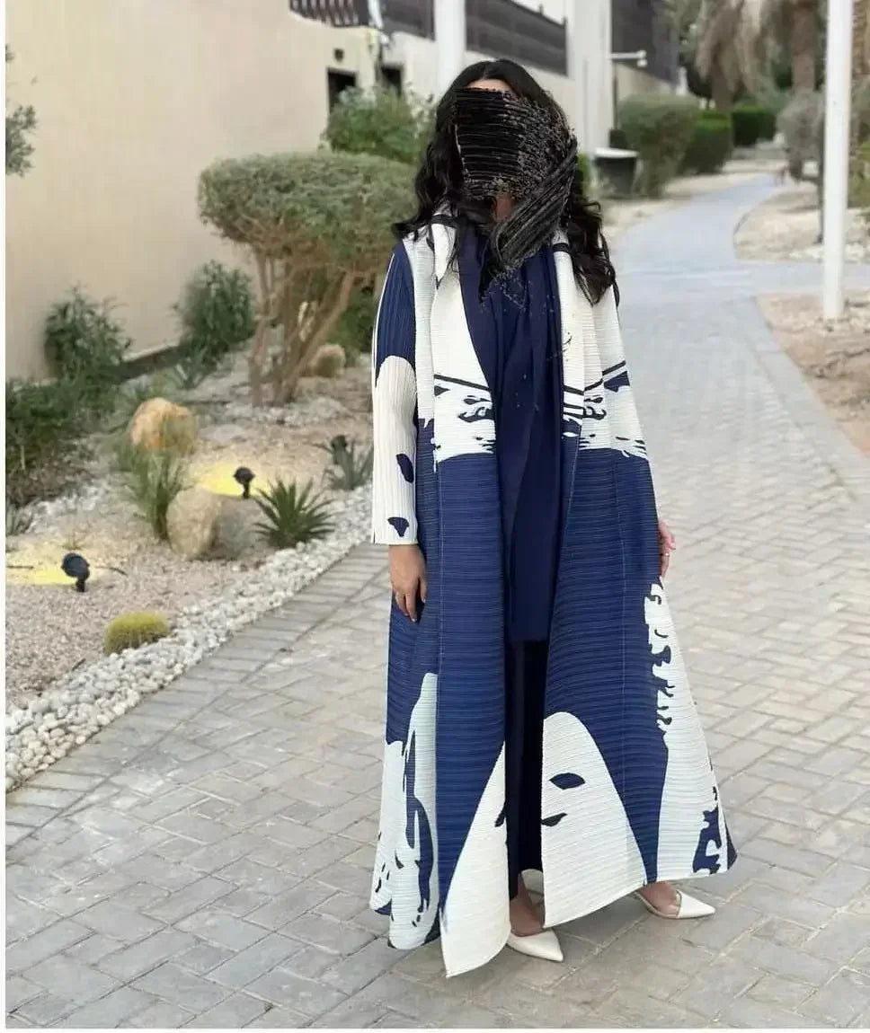 Une femme portant un trench-coat à manches longues à plis bleu et blanc marche sur un chemin pavé.
