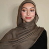 Eine Frau trägt einen einfarbigen braunen Gradient-Rayon-Hijab und schwarze Kleidung.