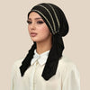 Eine Frau trägt ein schwarzes Hijab mit einem goldenen Streifen-Elastband und einem weißen Hemd.