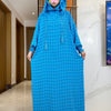 Una mujer vistiendo una abaya de algodón azul brillante con puntos negros y una mascarilla de flor rosa.